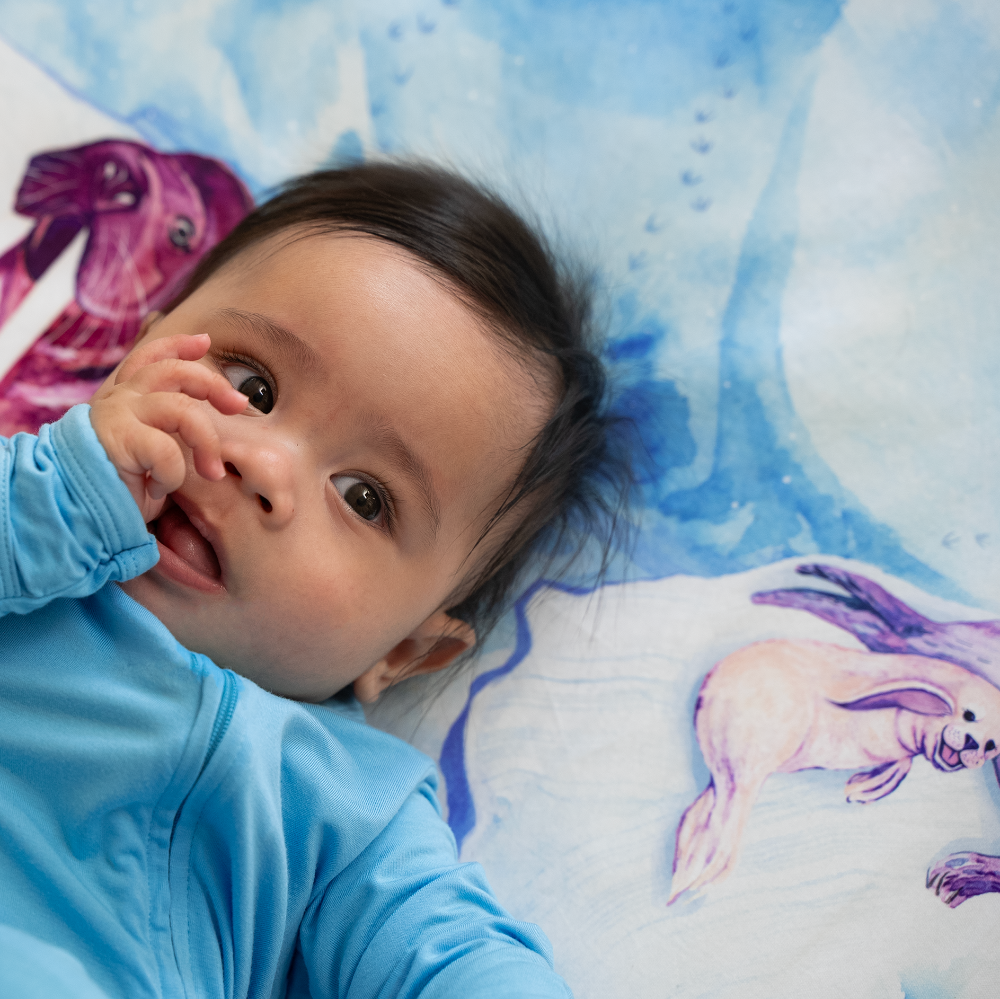 baby looking relaxed on arctic themed crib sheet