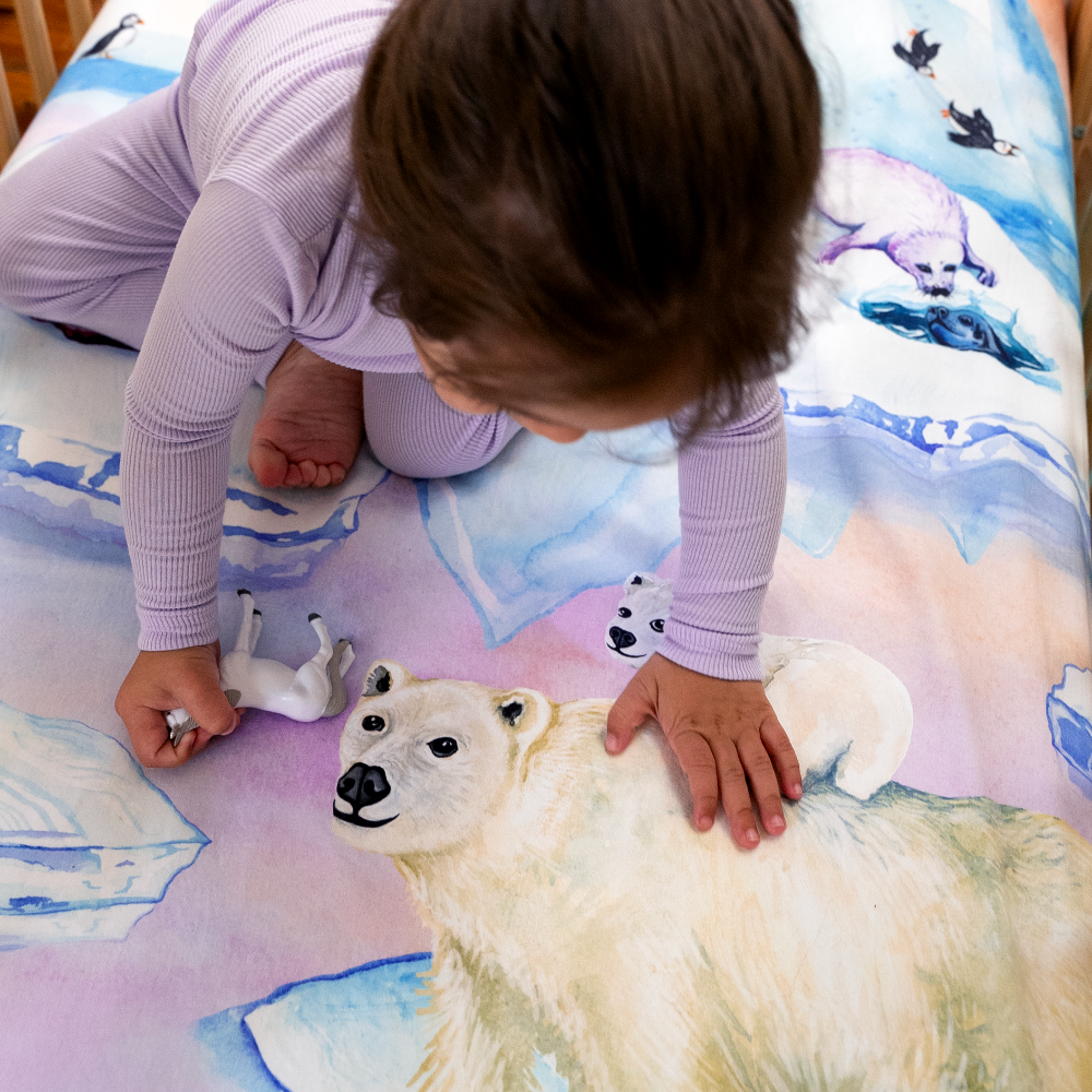 toddler looking at polar bear illustration on arctic themed sheet