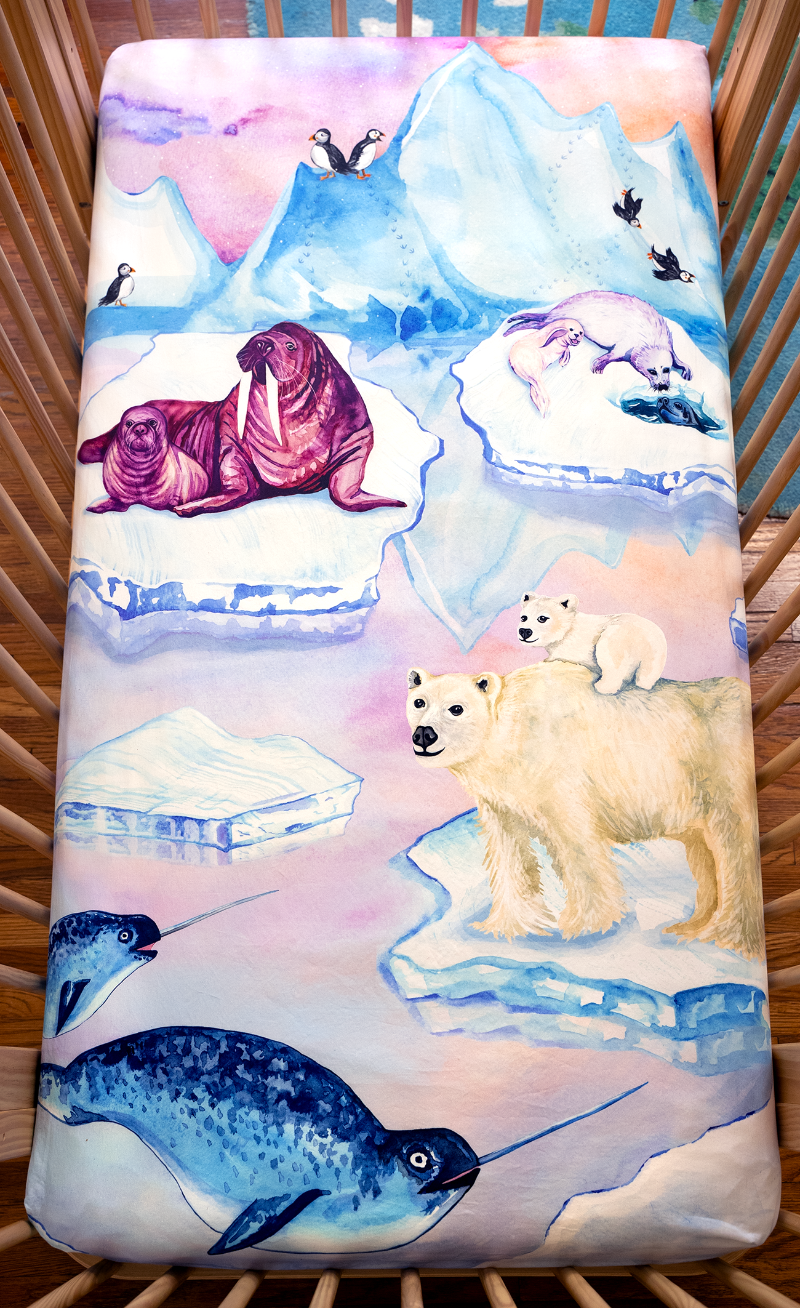 arctic themed crib sheet featuring seals, walruses, polar bears, narwhals, and puffins in a snowy, icy scene